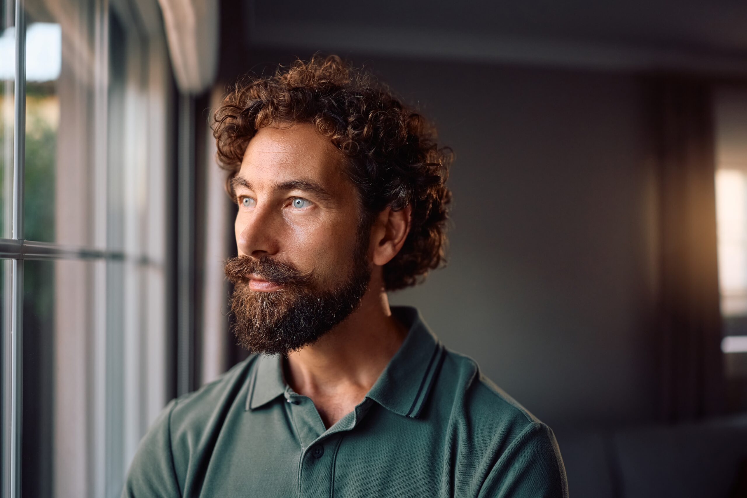 Pensive man looking out window thinking about how his partner does not want to have sex